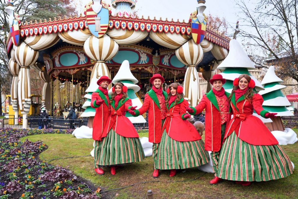 Personaggi in costumi natalizi posano davanti alla grande giostra a cavalli di Gardaland durante l'apertura invernale 
