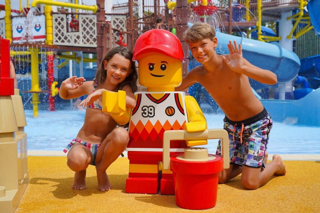 Bambini posano per una foto vicino ad un omino Lego all'interno del Legoland Water Park di Gardaland Resort
