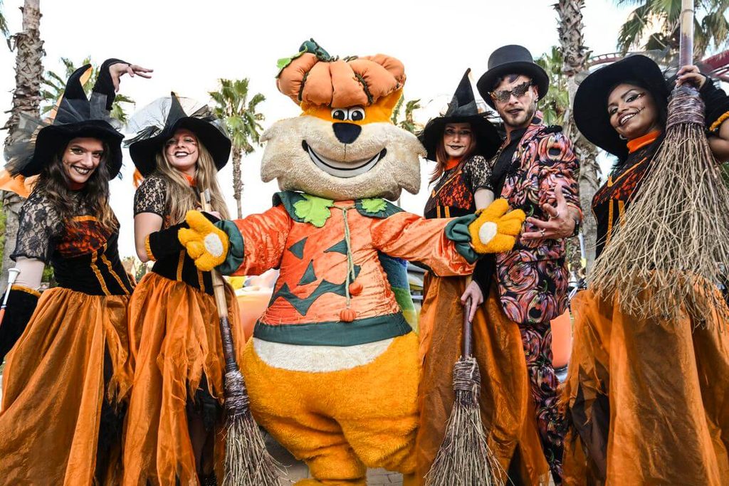 La mascotte Gattobaleno di Magicland con il costume da Halloween insieme a delle streghe