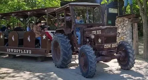 Convoglio di vagoni trainati da un trattore al parco Cowboyland