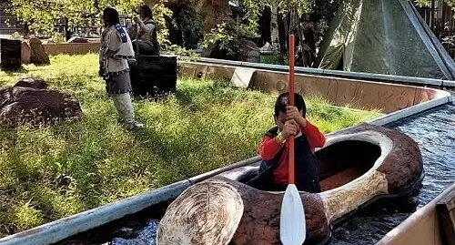Bambina naviga su una canoa a forma di tronco galleggiante