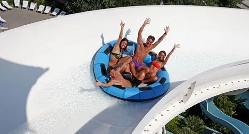 Ragazzi felici scendono lungo uno scivolo con gommone del parco acquatico a Riccione